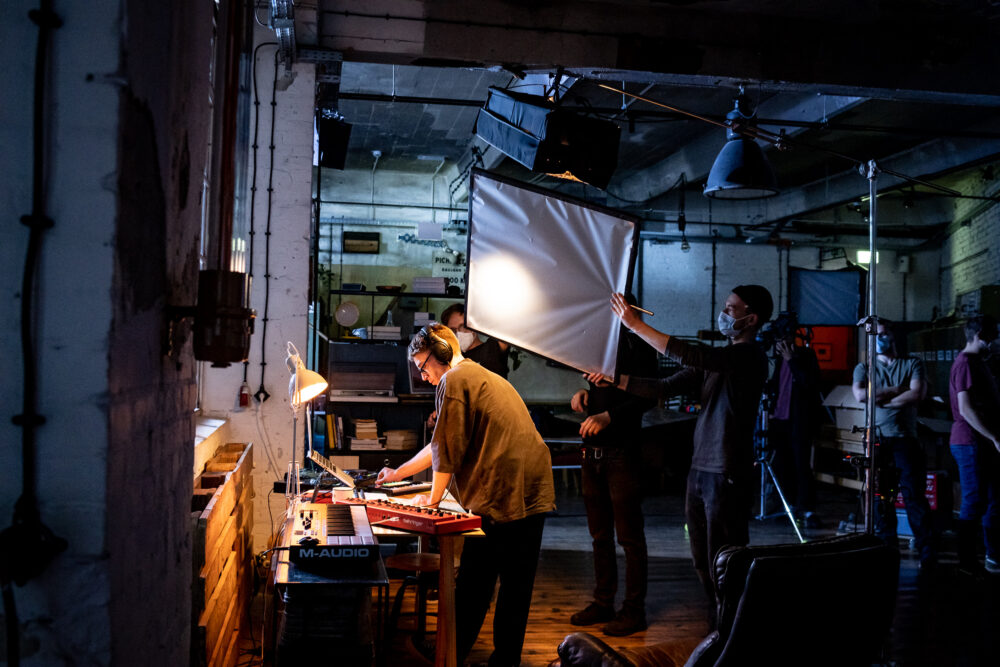 In einem cineastisch ausgeleuchtetem Raum arbeitet ein Team aus Filmschaffenden an einem Produktfilm für einen Kunden.