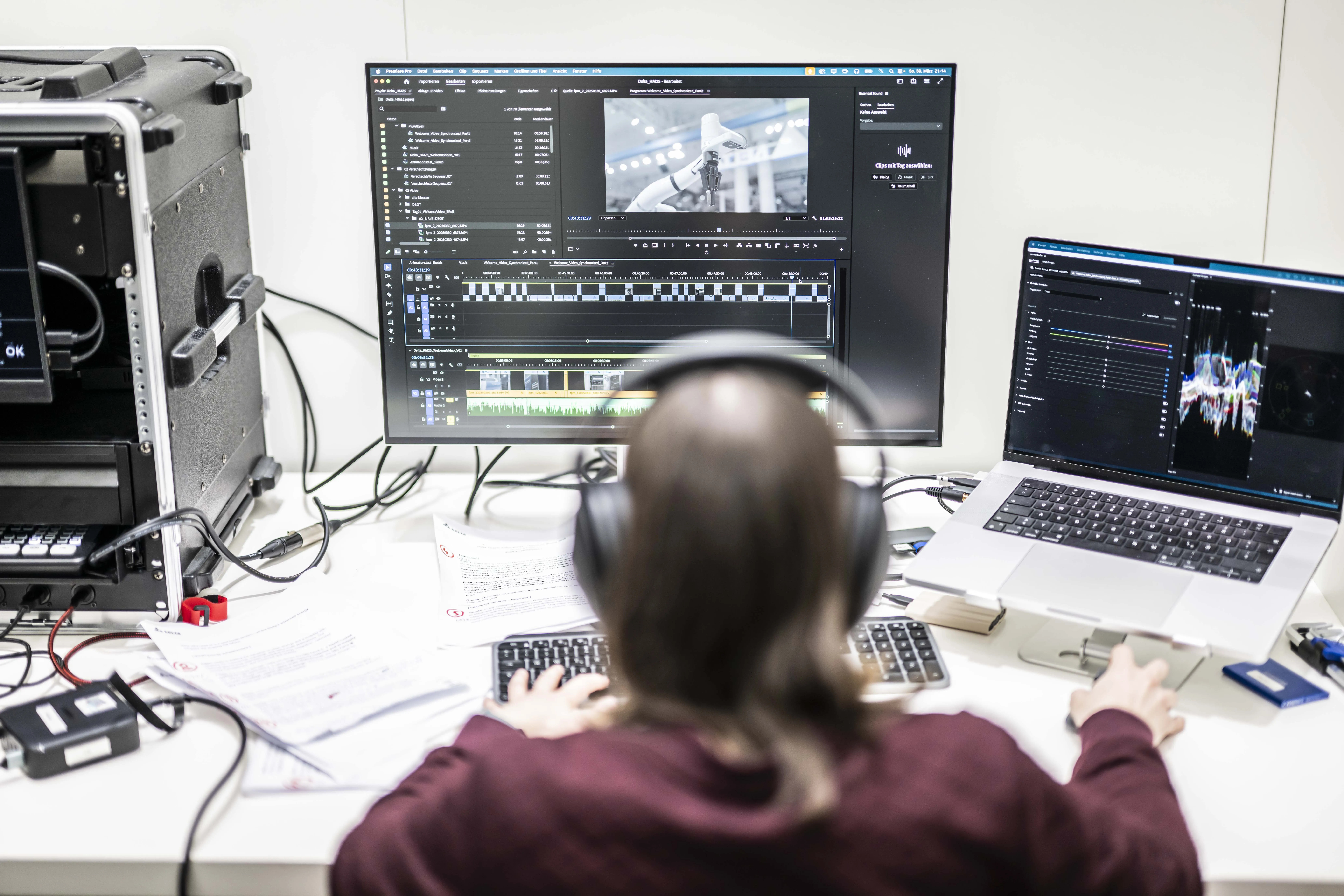 Eine Cutterin sitzt auf einem Messestand an einem Videoschnittplatz und schneidet ein Messevideo.
