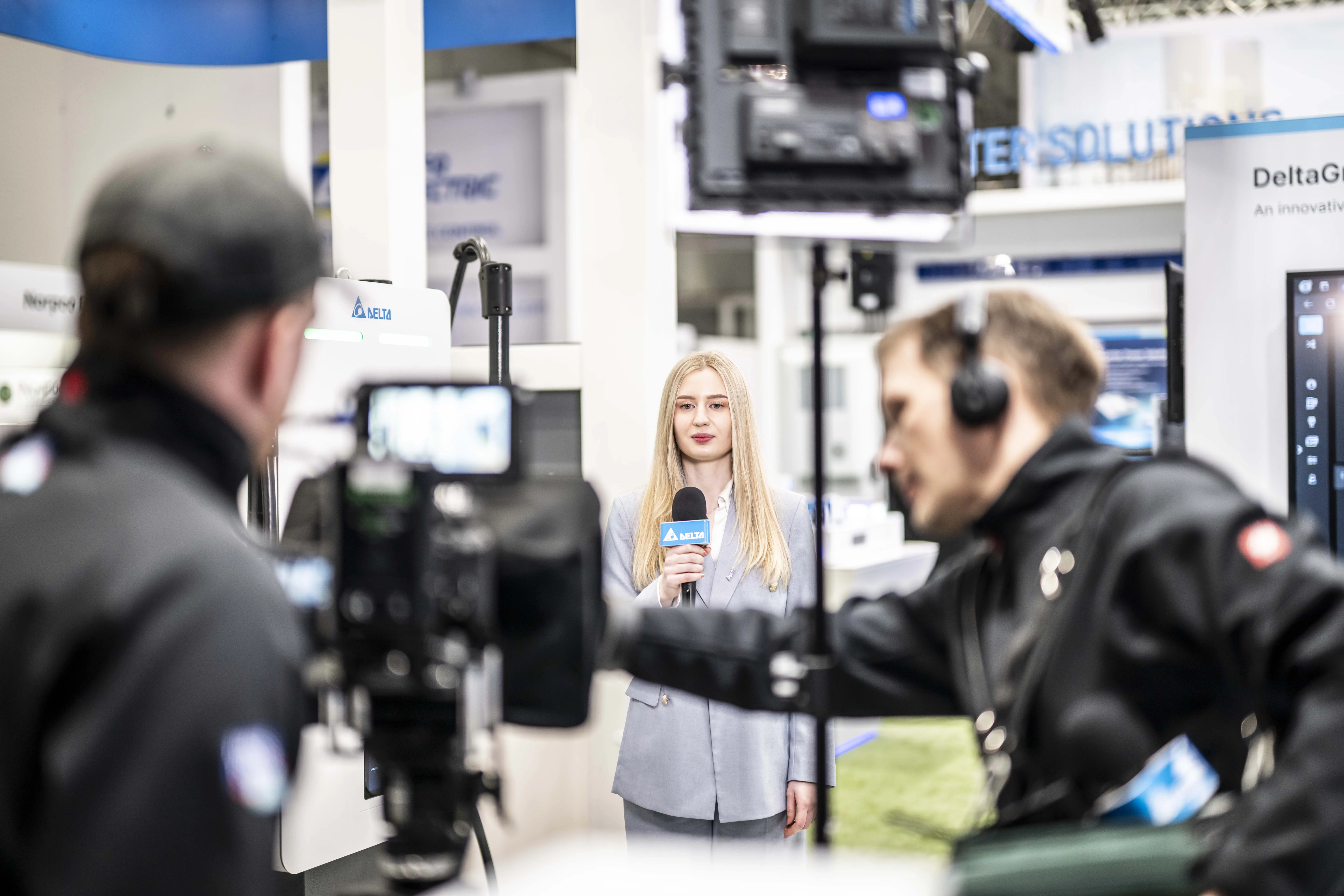 Zwei Kameraleute filmen eine Moderatorin auf einem Messestand von Delta Electronics auf der Hannover Messe