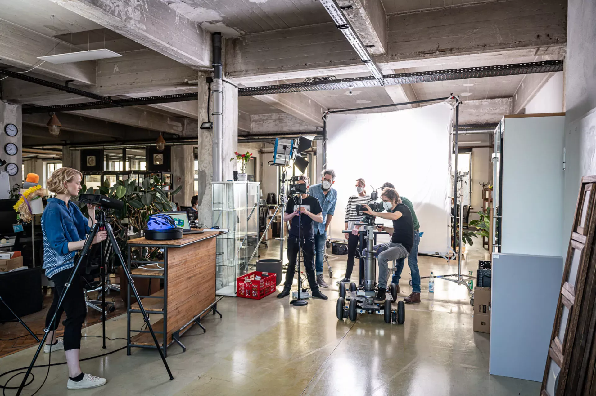 Eine Filmcrew mit einem Kamera-Dolly und Lichtequipment in einer Industriehalle während einer Filmproduktion für einen Konzern.