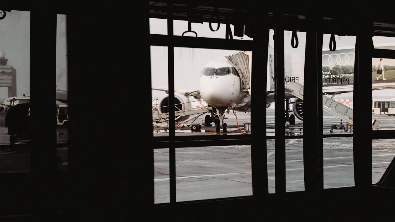 Flugzeug am Flughafen durch ein Fenster eines Terminals fotografiert.