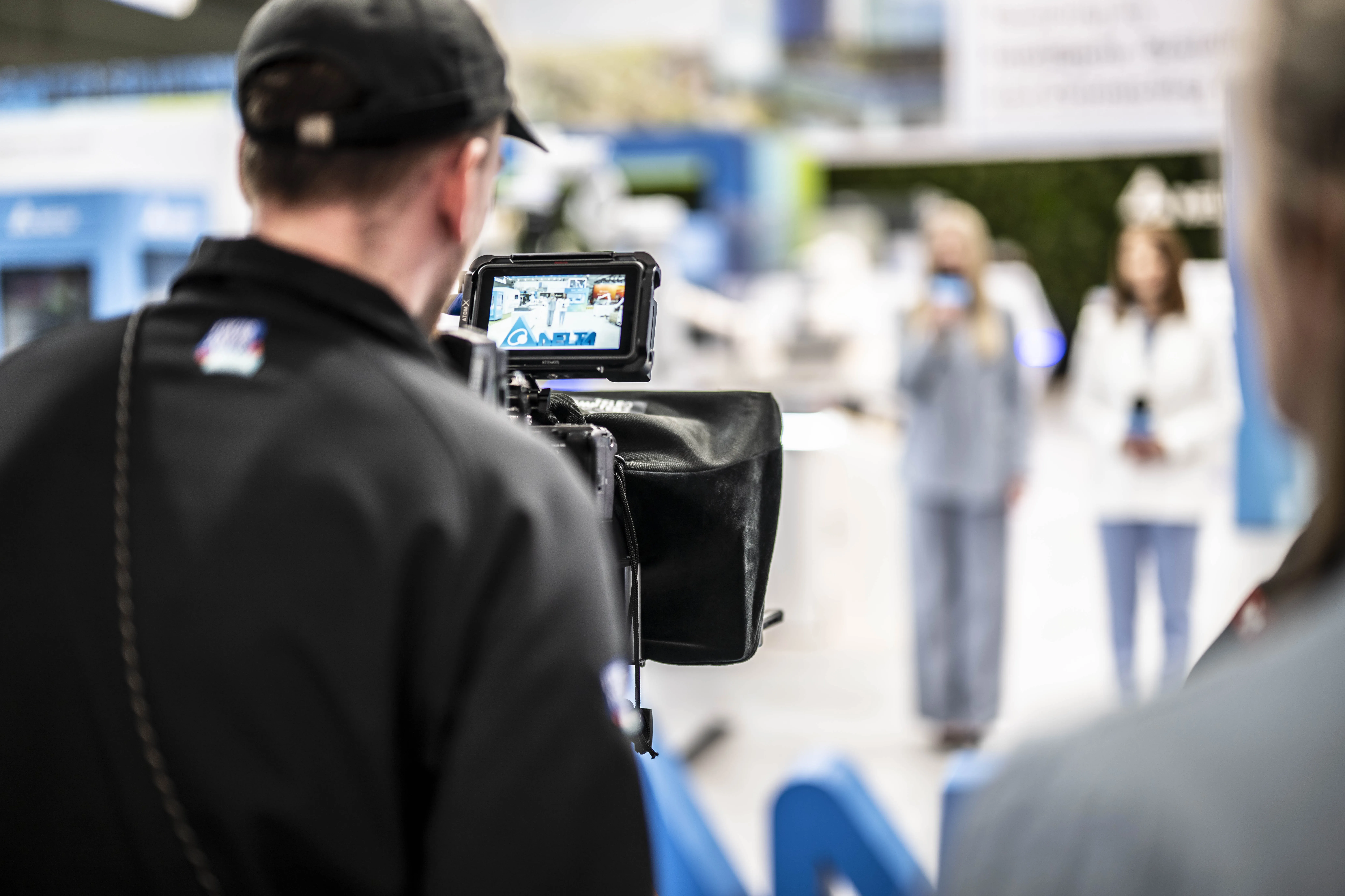 Blick über die Schulter eines Kameramanns auf seine Kamera bei der Aufnahme eines Videos auf dem Messestand von Delta Electronics auf der Hannover Messe