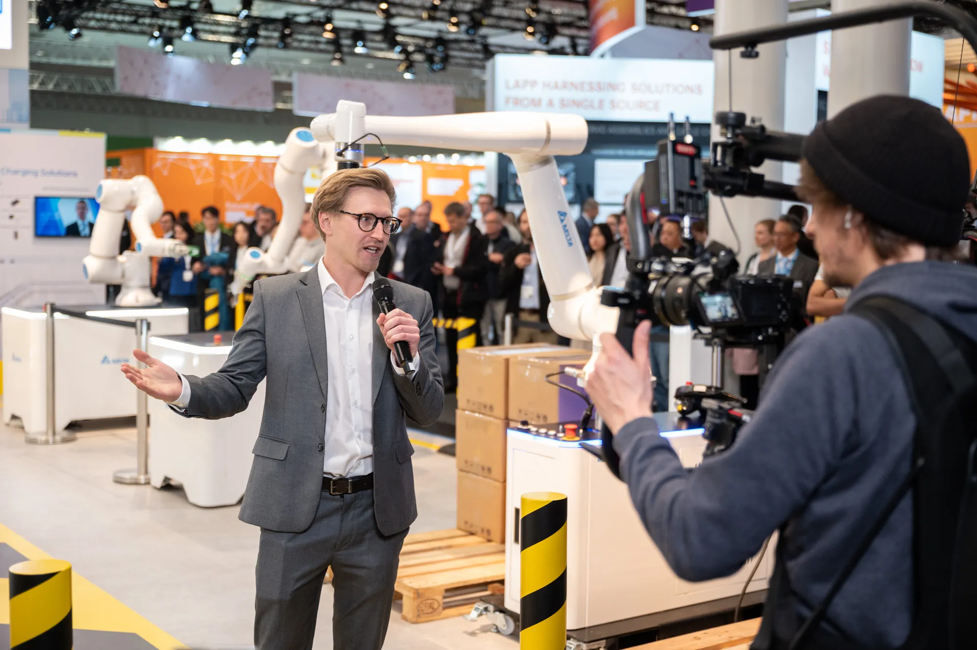 Ein Kameramann filmt einen Moderator auf einem Messestand während einem Livestream.