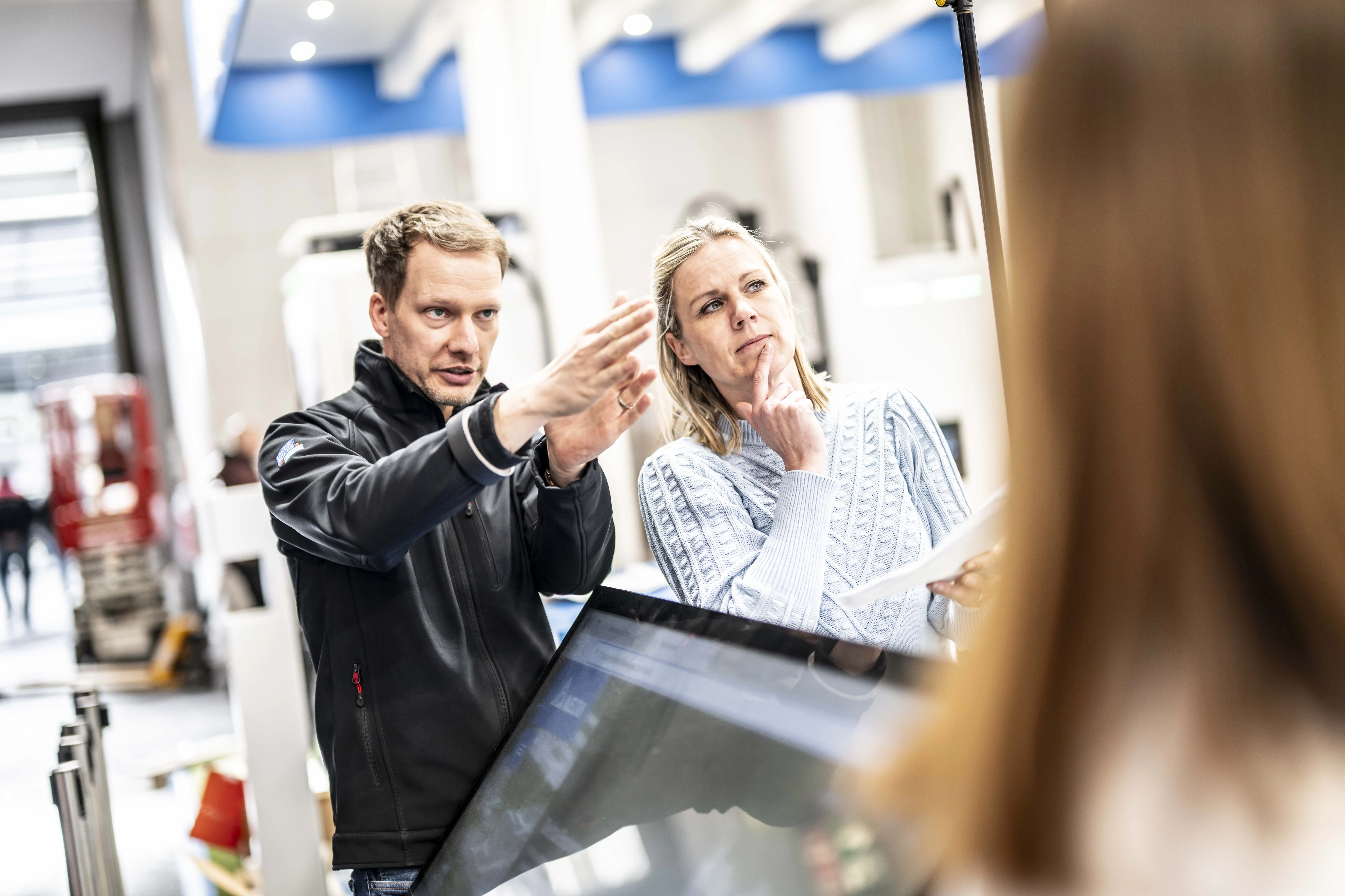 Ein Projektmanager bespricht auf einer Messe den Bildausschnitt mit dem Kunden
