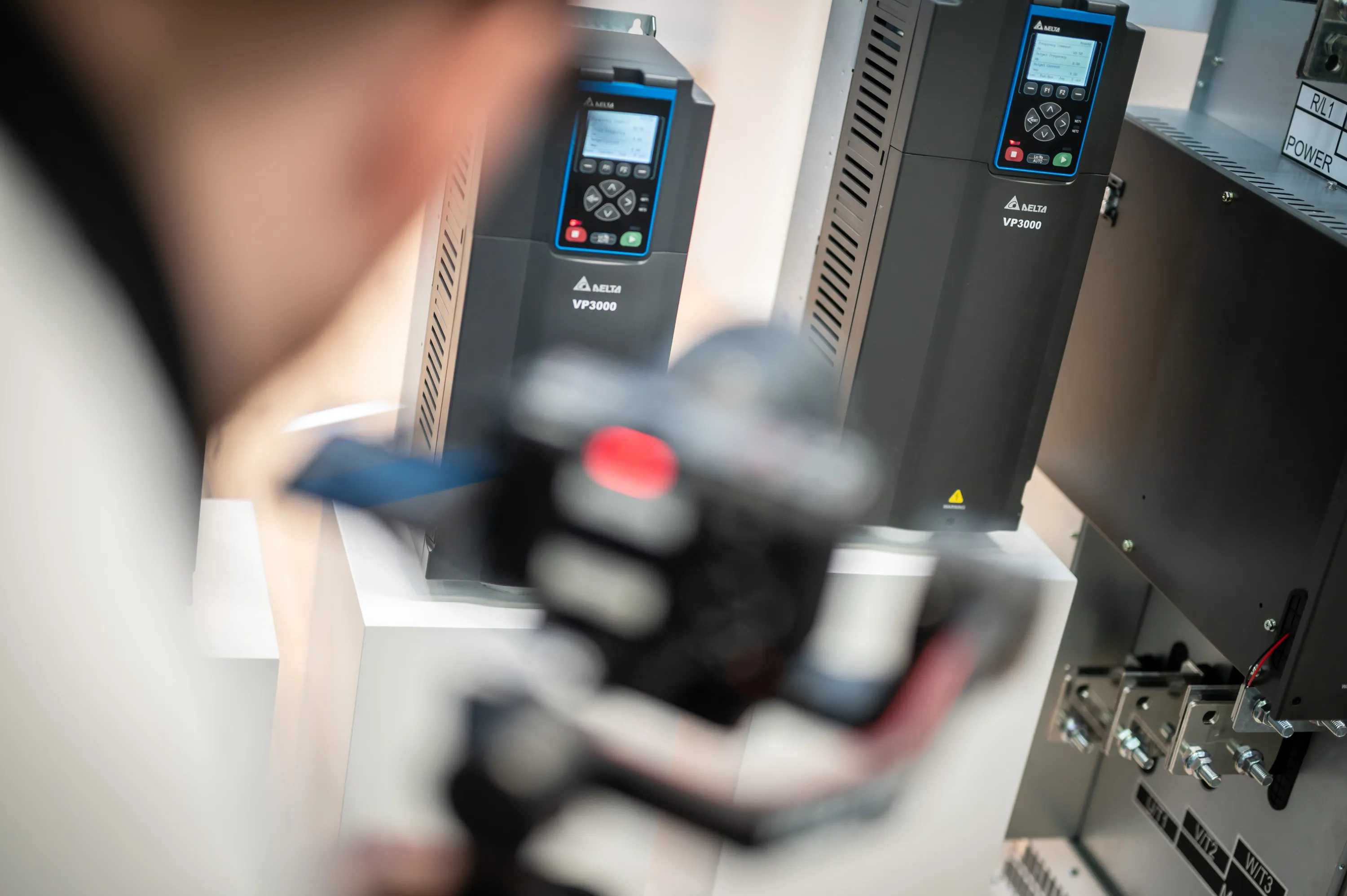 Eine unscharfe Kamera im Vordergrund mit einem Ausstellerprodukt auf einer Messe in Hannover im Hintergrund