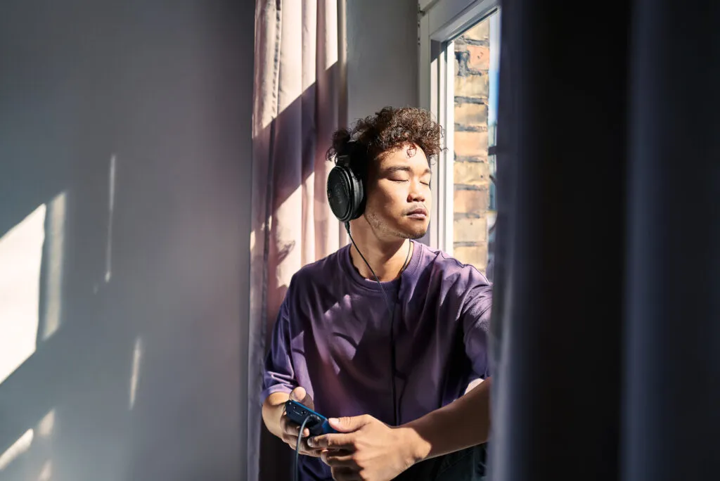 Mann hört mit Sennheiser HD 660S2 am sonnigen Fenster Musik