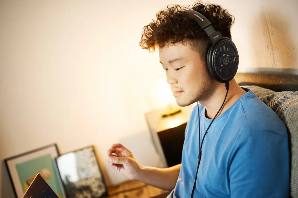 Mann mit Sennheiser HD 660S2 Kopfhörer beim Musikhören auf dem Sofa