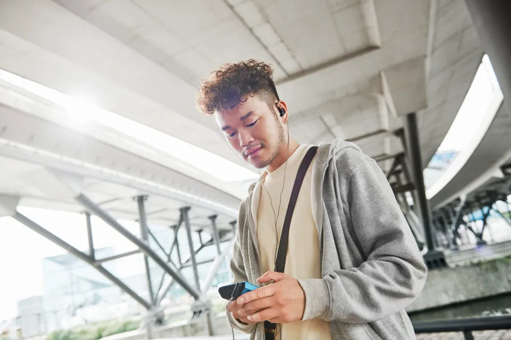 Mann hört unterwegs mit Sennheiser IE 200 und mobilem Musikplayer