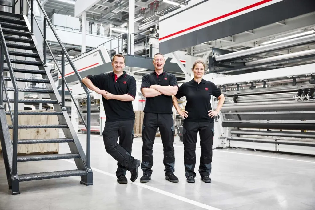 Mitarbeiter von Windmöller & Hölscher vor einer großen Produktionsanlage