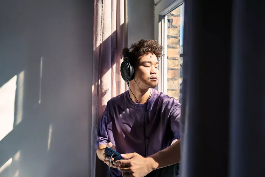 Mann hört mit Sennheiser HD 660S2 am sonnigen Fenster Musik