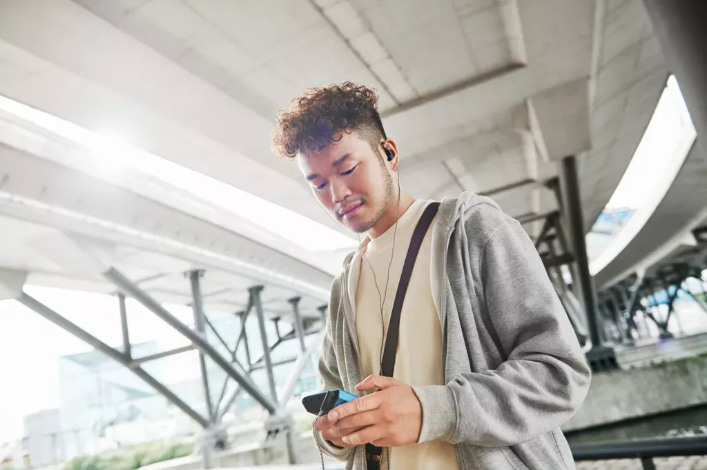 Mann hört unterwegs mit Sennheiser IE 200 und mobilem Musikplayer