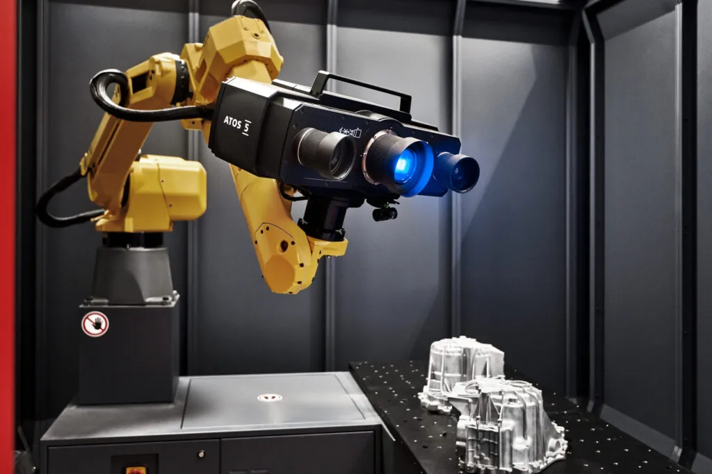 Ein Scanner auf einem Robotterarm strahlt blaues Licht auf ein Produkt
