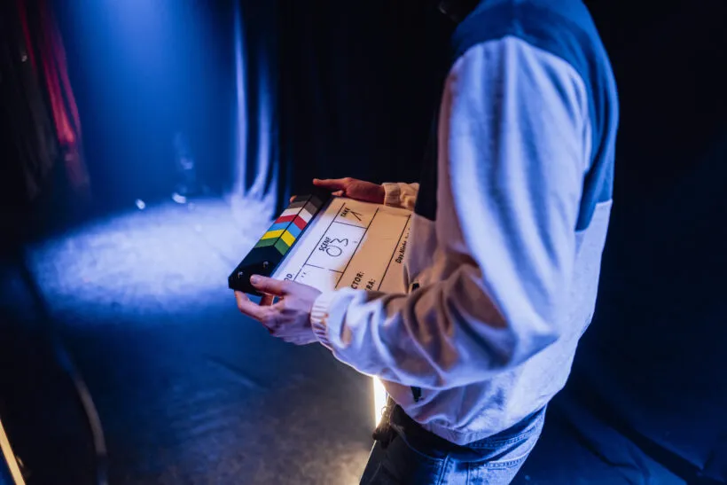 Ein Assistent am Filmset hält eine Filmklappe in der Hand.