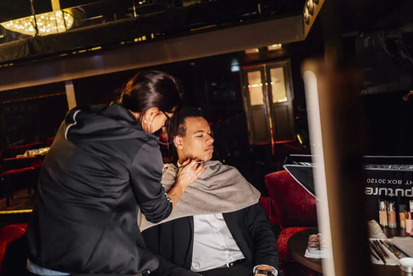 Make-up Artist trägt mit einem Pinsel Make-up auf das Gesicht einer Person auf.