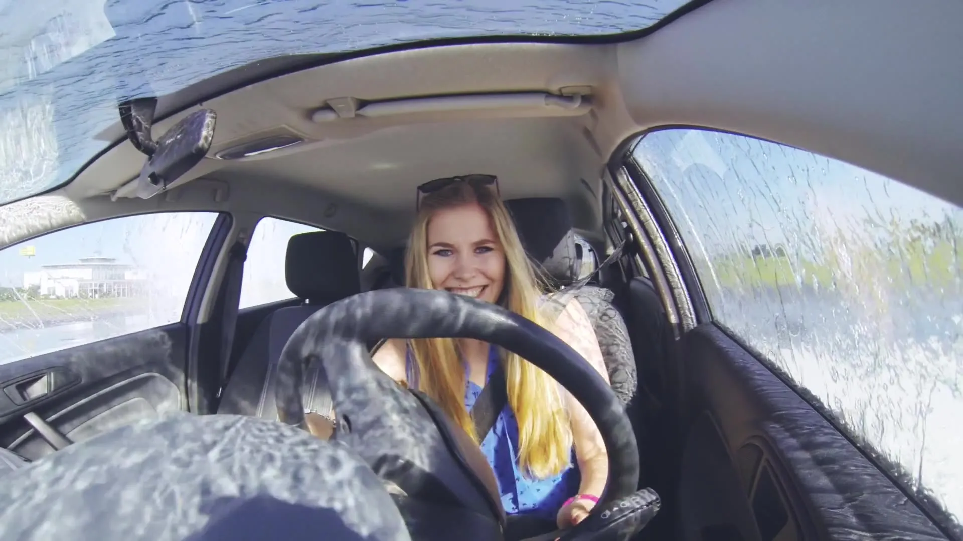 Eine GoPro-Kamera zeigt eine lachende Frau im Fahrzeug bei einer Veranstaltung zu einem Fahrsicherheitstraining.